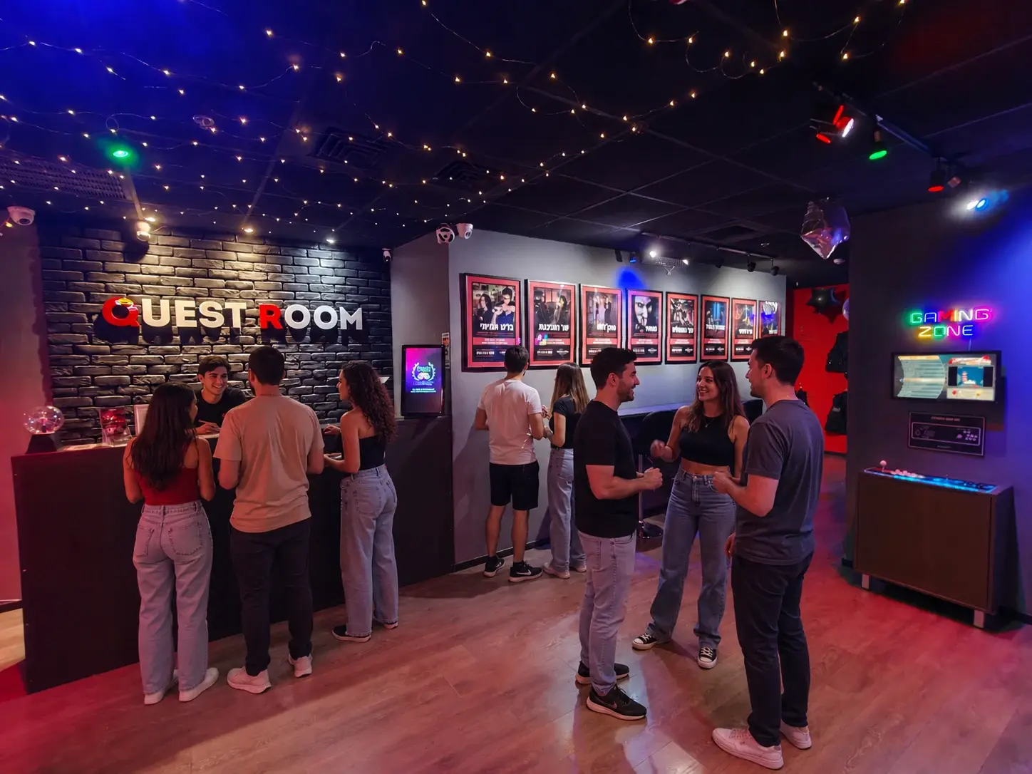 אורחים בלובי Quest Room מול קיר הלוגו ותמונות החדרים